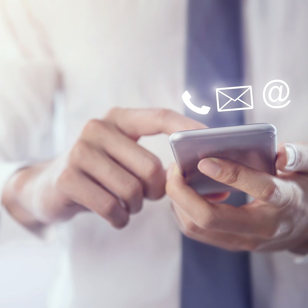 Ein Mann in Hemd und Krawatte hält ein Handy in der Hand.